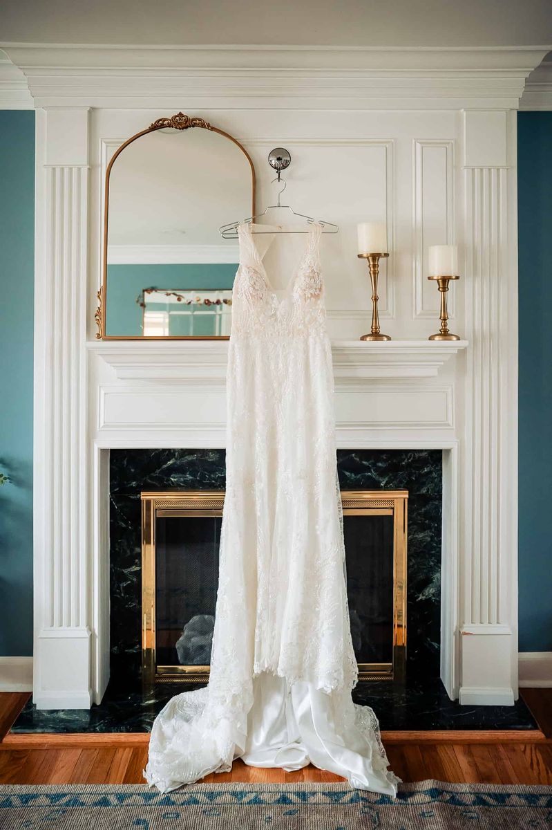 Wedding gown hanging beside a fireplace mantel