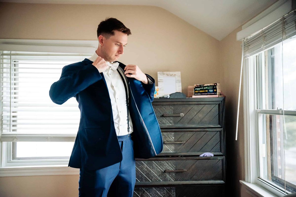 Groom putting on his navy jacket