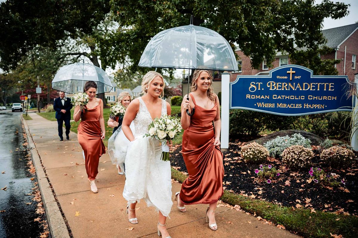 Bride and bridesmaids arriving at the church under an umbrella