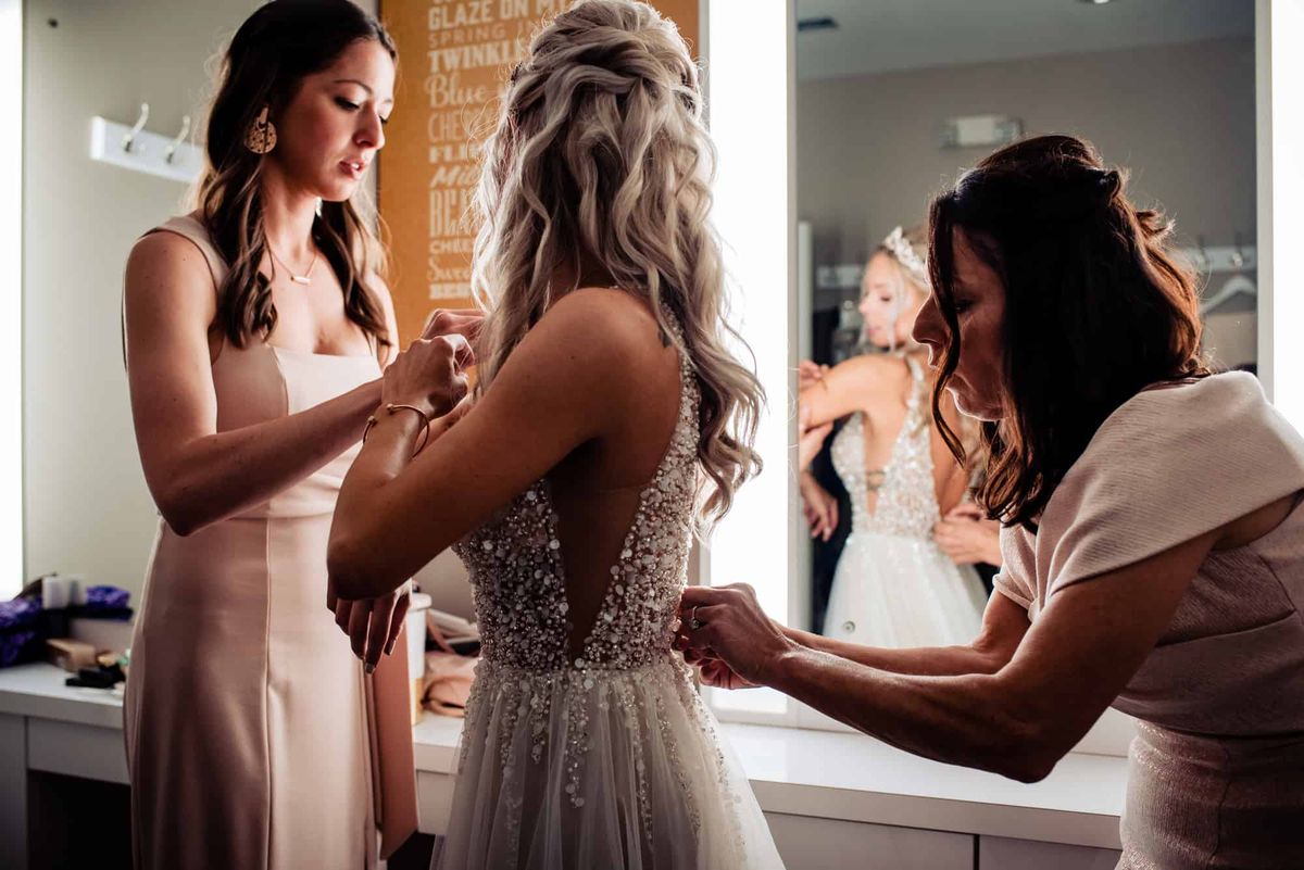 Bridesmaids helping the bride into her gown